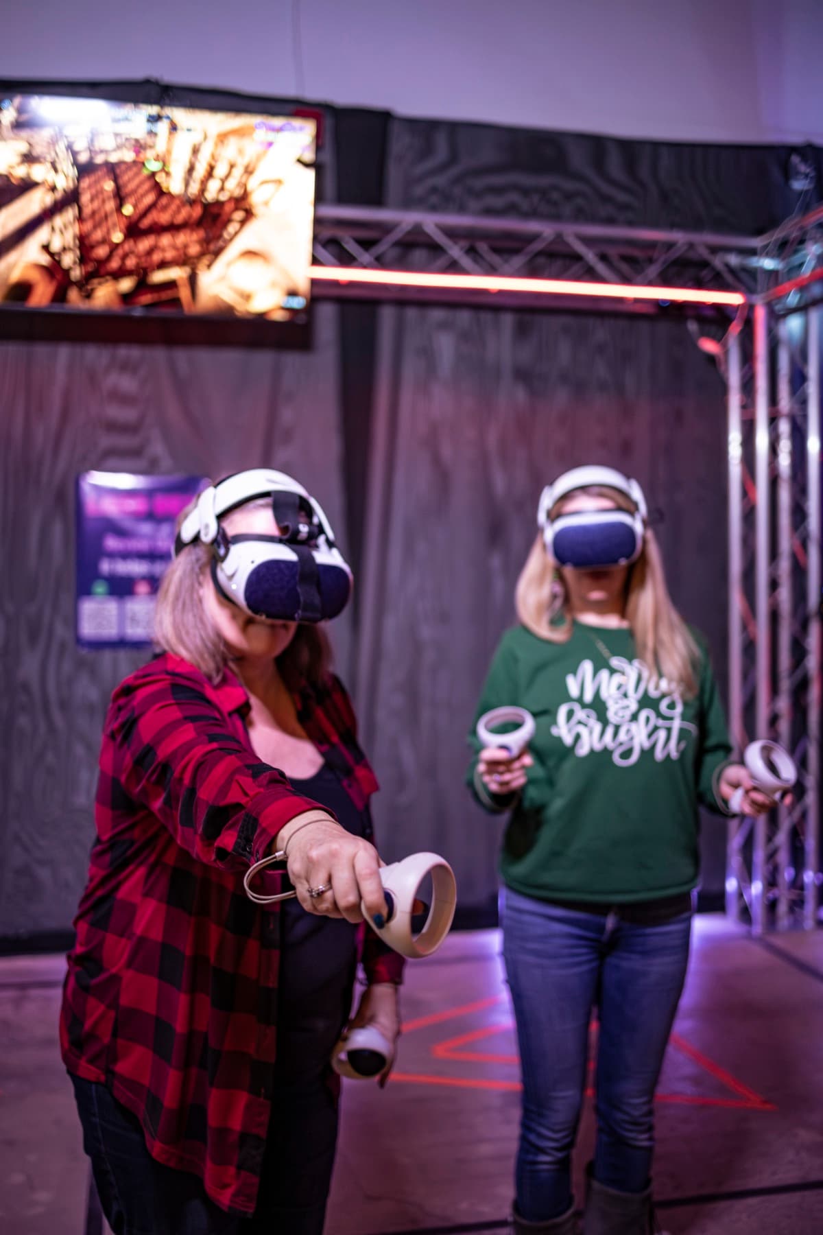 Two coworkers in Christmas sweaters playing VR side by side