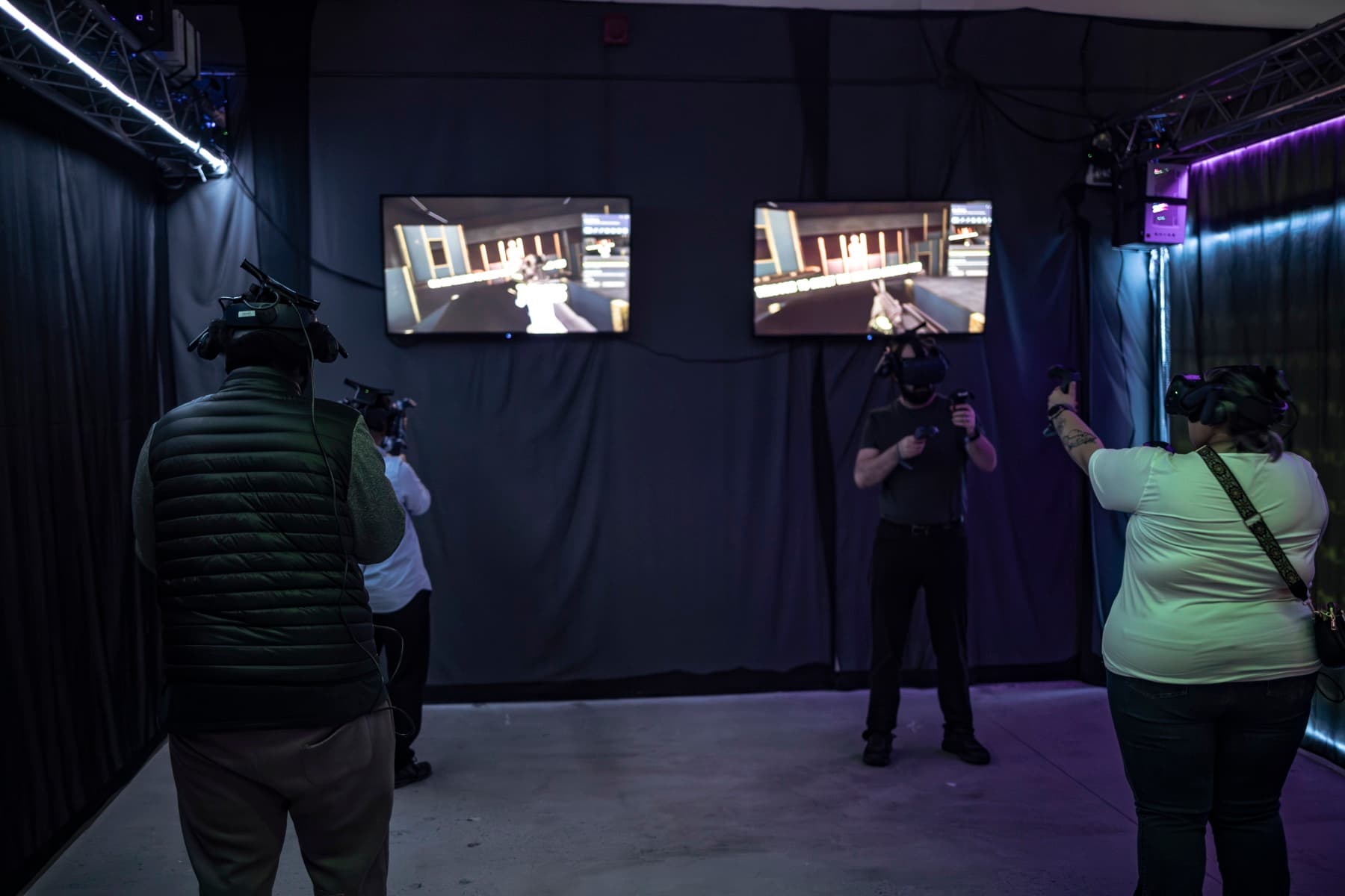 Three players in VR headsets with spectator screens mirroring their games